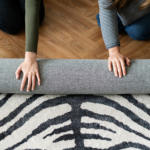 Dos personas enrollando una alfombra