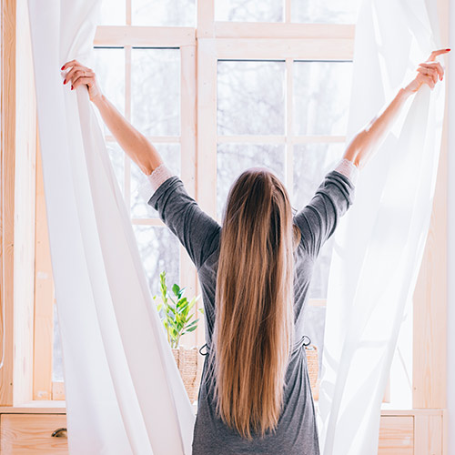 Mujer abriendo las cortinas